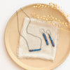 The lapis beaded bar earrings styled on a tan plate with the matching necklace with linen and dried grass