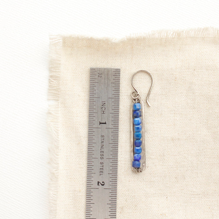 A lapis beaded bar earring next to a ruler for size reference