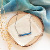 The lapis beaded bar necklace styled on wood with blue velvet and dried grass