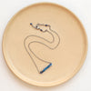 The lapis beaded bar necklace styled on a tan plate to show the adjustable lobster clasp closure