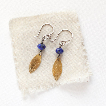 The lapis and brass leaf earrings styled on tan linen