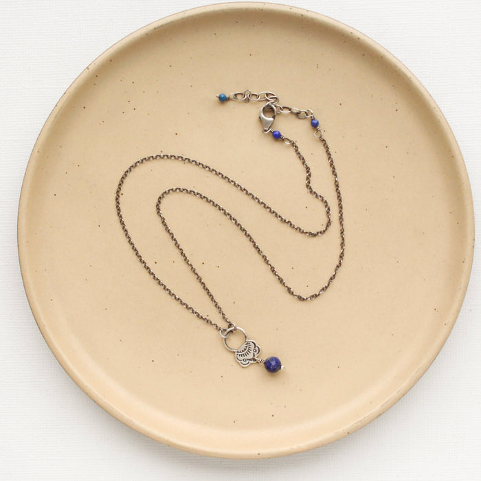 The lapis jolie necklace styled on a tan plate to show the adjustable lobster clasp closure