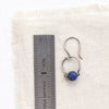 A lapis la cloche earring next to a ruler for size reference