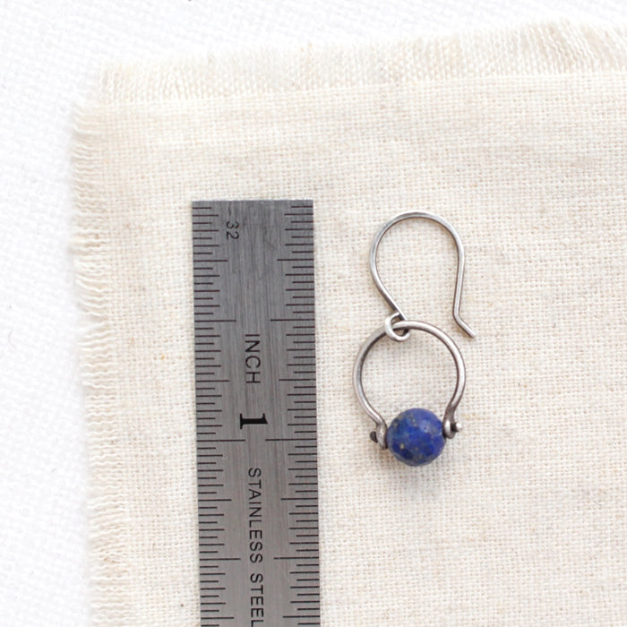 A lapis la cloche earring next to a ruler for size reference