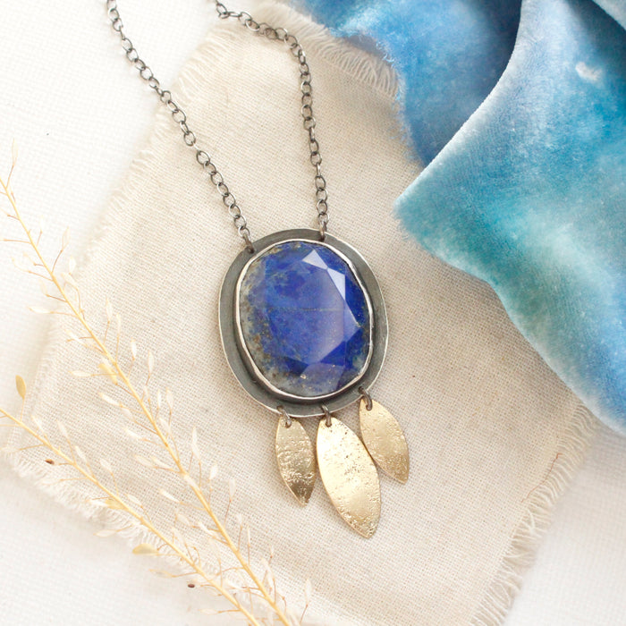 The lapis and brass leaf long necklace styled on tan linen with blue velvet and dried grass