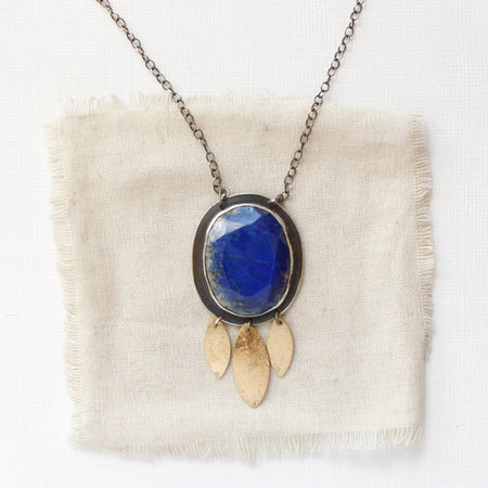 The lapis and brass leaf necklace styled on tan linen