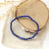 The lapis stretch bracelet styled on wood with linen and dried grass