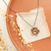 The bronze layered cactus flower necklace styled on an orange plate with linen and dried grass