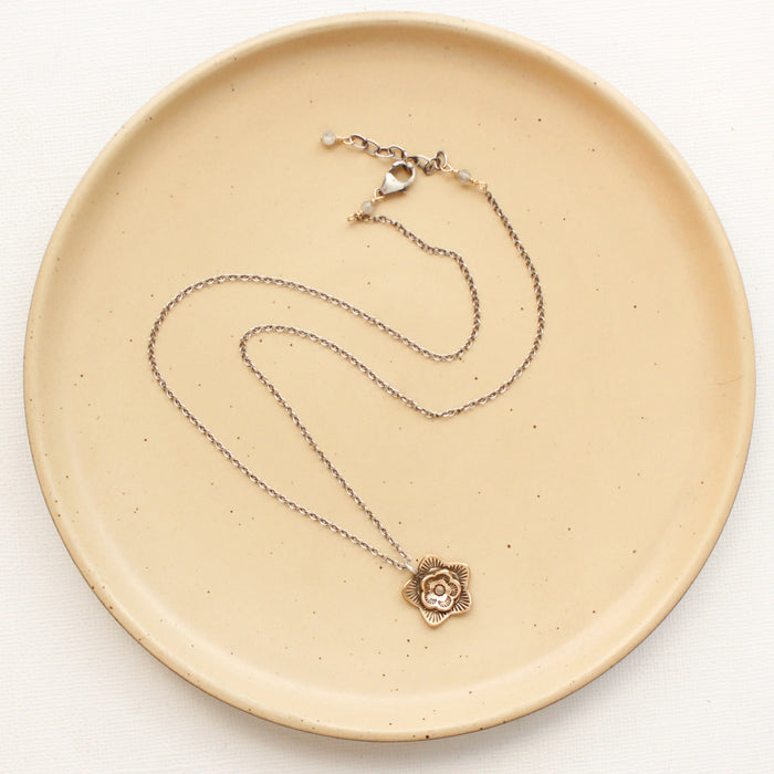 The bronze layered cactus flower necklace styled on a tan plate to show the adjustable lobster clasp closure