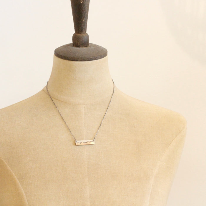 A mannequin wearing the oxidized silver mountain bar necklace