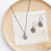 The layered soar necklace styled on a plate with the matching earrings