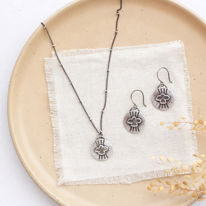 The layered soar necklace styled on a plate with the matching earrings