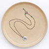 The layered soar necklace styled on a tan plate to show the adjustable lobster clasp closure