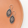 The layered sprout earrings on an orange plate