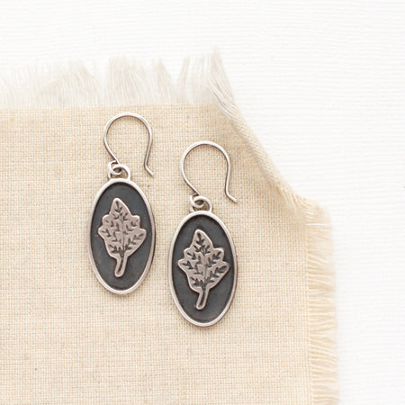 The layered sprout earrings styled on tan linen