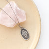 The layered sprout necklace styled on a tan plate with a pink stone