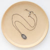 The layered sprout necklace styled on a tan plate to show the adjustable lobster clasp closure
