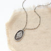 The layered sprout necklace styled on tan linen