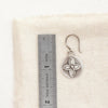 A layered wanderer coin earring next to a ruler for size reference