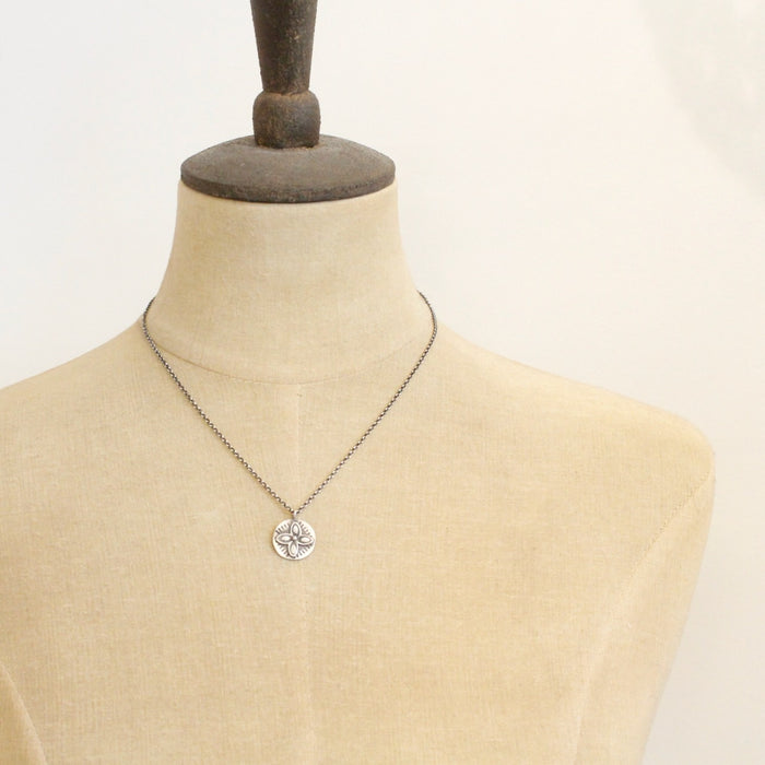 A mannequin wearing the layered wanderer coin necklace