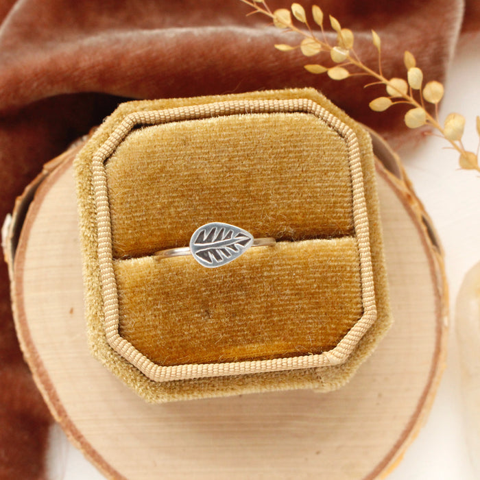 The leaf stacking ring styled in a yellow box on wood with orange velvet and dried grass