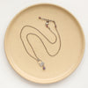 The lepidolite jolie necklace styled on a tan plate to show the adjustable lobster clasp closure
