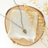 The bronze leaf necklace styled on wood with linen and dried grass
