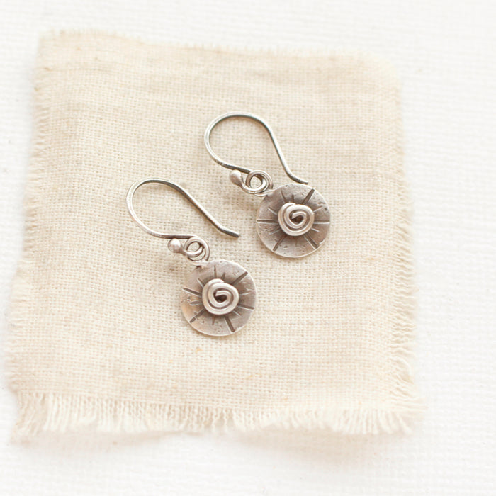 The mini musana earrings styled on tan linen