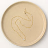 The little opal drop necklace styled on a tan plate to show the adjustable lobster clasp closure