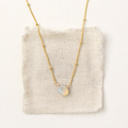 The little opal drop necklace styled on tan linen