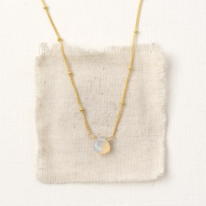 The little opal drop necklace styled on tan linen