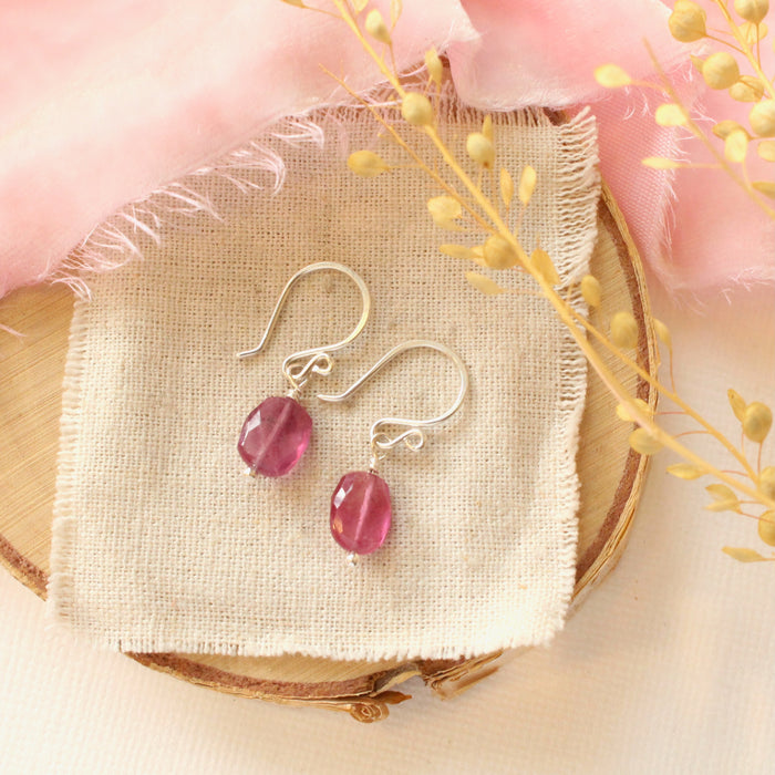 The little ruby earrings in silver styled on wood with linen, pink velvet, and dried grass