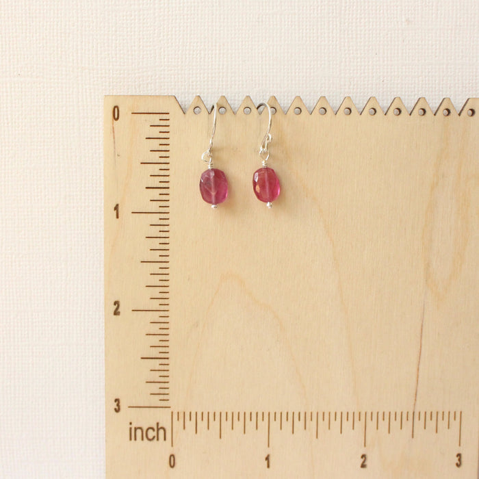 The little ruby earrings in silver on a wooden ruler for size reference
