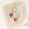 The little ruby earrings in silver styled on tan linen