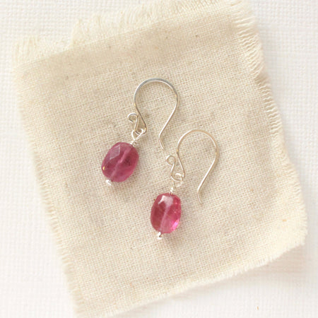 The little ruby earrings in silver styled on tan linen