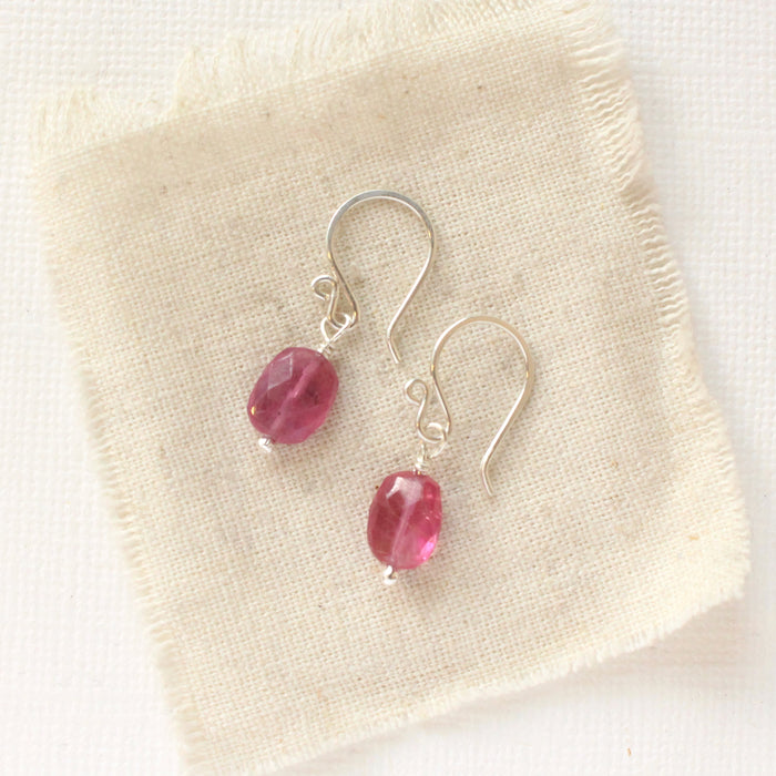 The little ruby earrings in silver styled on tan linen