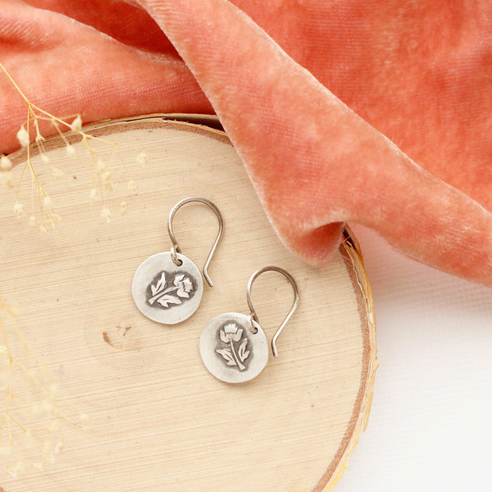 The little rustic rose earrings styled on wood with orange velvet and dried grass