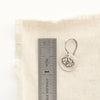 A little rustic rose earring next to a ruler for size reference