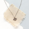 The mini soar necklace styled on tan linen 