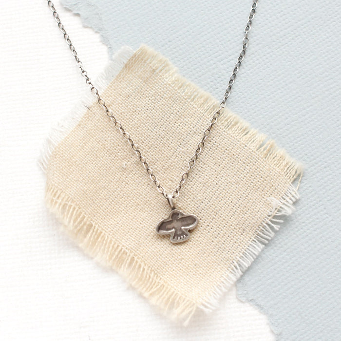 The mini soar necklace styled on tan linen 