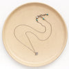 The mini soar necklace on a tan plate to show the adjustable lobster clasp closure