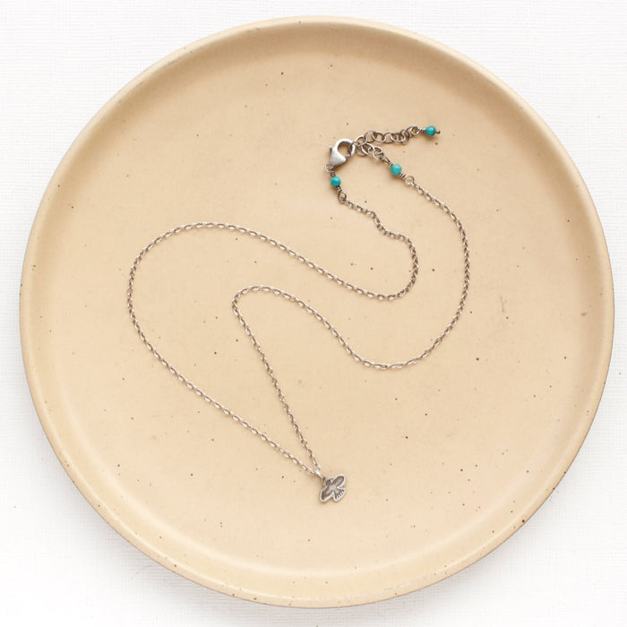 The mini soar necklace on a tan plate to show the adjustable lobster clasp closure