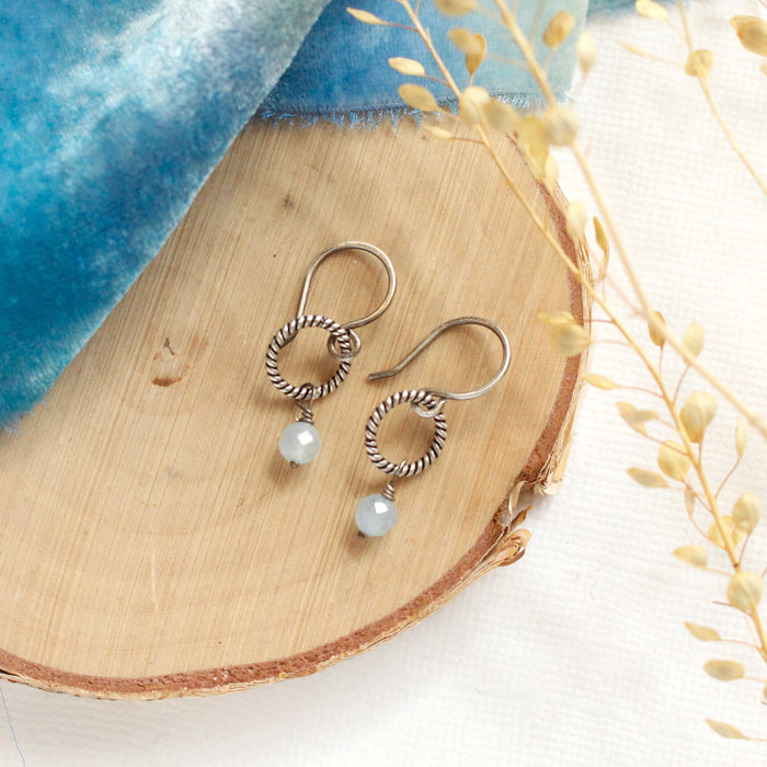 The aquamarine silver hoop earrings styled on wood with blue velvet and dried grass