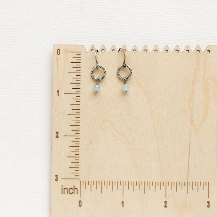 The little aquamarine hoop earrings styled on a wooden ruler