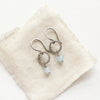 The aquamarine hoop earrings styled on tan linen