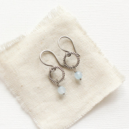 The aquamarine hoop earrings styled on tan linen