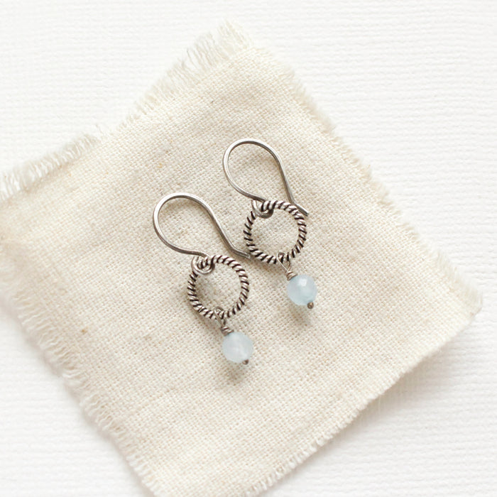 The aquamarine hoop earrings styled on tan linen