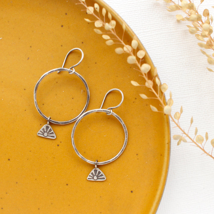 The sun rise hoop earrings styled on a yellow plate with dried grass