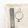 A sun rise hoop earring next to a ruler for size reference