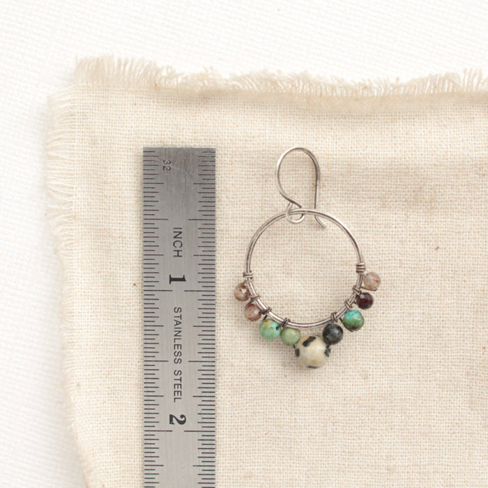 A lona hoop earring next to a ruler for size reference